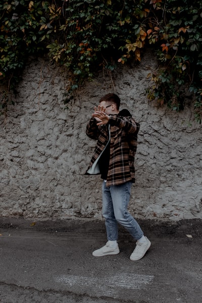 Dressed in a dark brown stripe long sleeve shirt and blue denim jeans lady standing beside the gray
